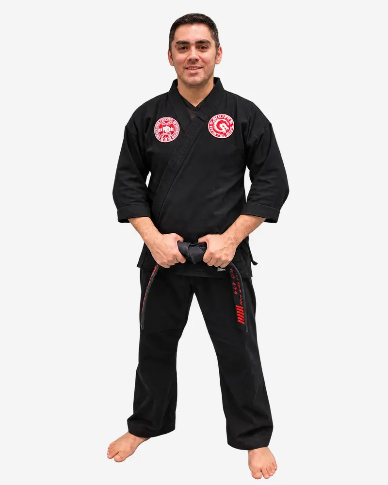 Professor Manny Galvan in a black martial arts uniform, holding his black belt