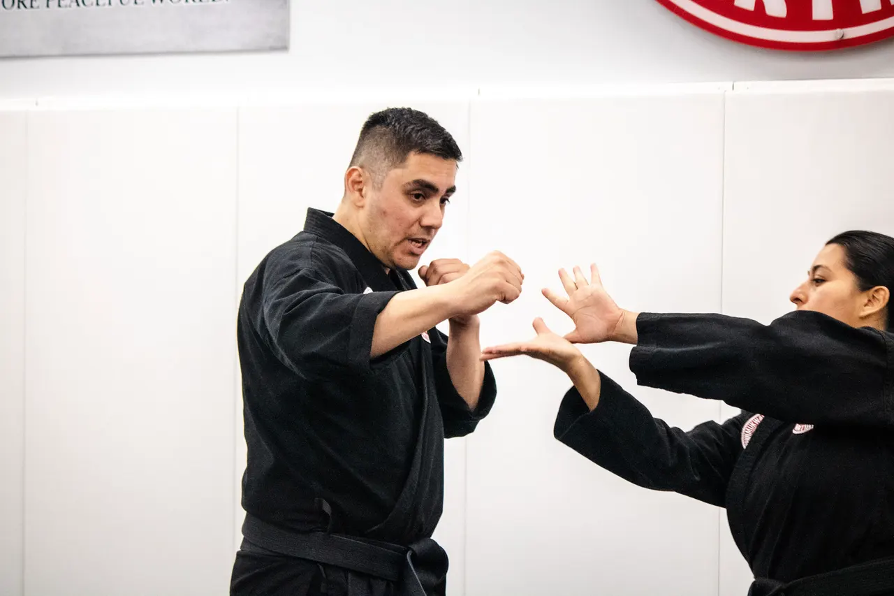 Professor Manny Galvan in a black uniform demonstrating a self-defense technique