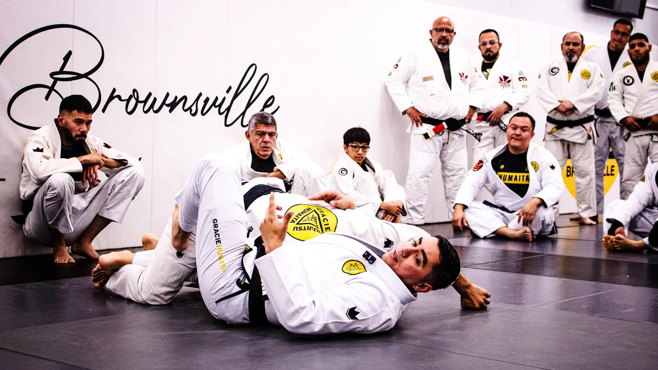 Professor Manny Galvan demonstrating a jiu-jitsu technique on the mat while seminar students watch