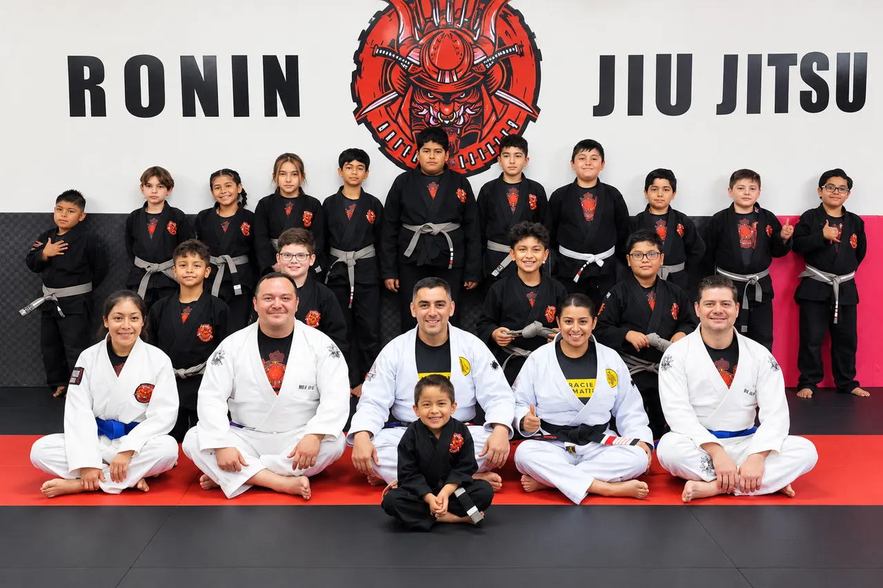 Professor Manny Galvan with instructors and young students in black gis after a kids jiu-jitsu seminar at Ronin Jiu Jitsu Academy in Matamoros, Mexico
