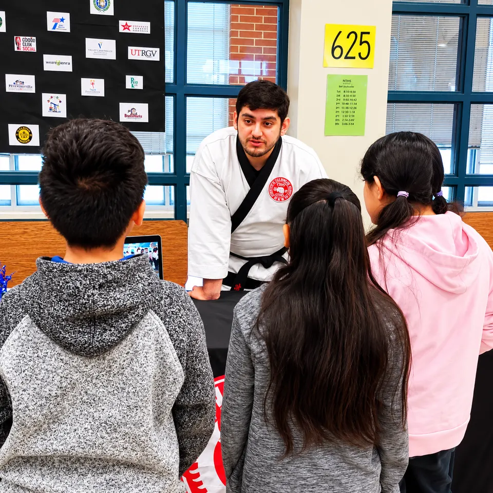 A Galvan’s Martial Arts instructor in a white gi talking with students at a school career day