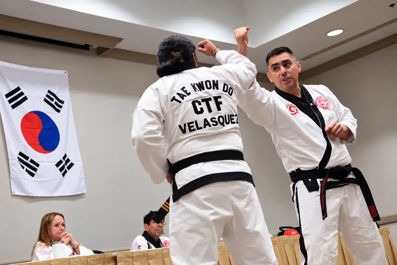 Professor Manny Galvan demonstrating a Tae Kwon Do technique on a student in a white uniform during a seminar